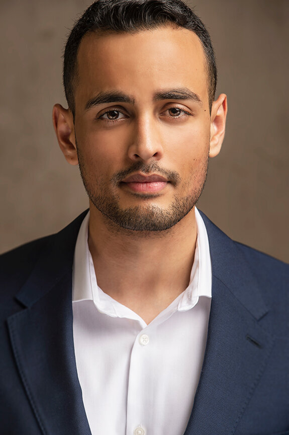 Professional corporate headshot of a man in a navy jacket against a neutral background, photographed in Dallas